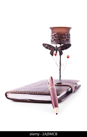 Close up di un pianificatore notebook con una penna e un vecchio portacandele, isolato su sfondo bianco. Foto Stock