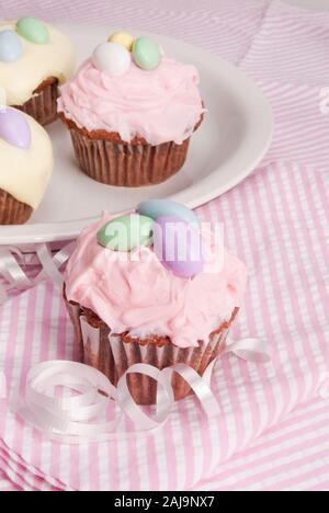 In casa Red Velvet tortine guarnita con crema di burro color pastello la glassa. Disco a forma di uovo di caramelle sono sulla parte superiore. Foto Stock