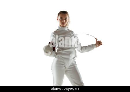 Campione. Teen ragazza in costume di scherma con la spada in mano isolati su sfondo bianco. Giovani modello femminile con la pratica e la formazione in movimento, l'azione. Copyspace. Sport, gioventù, uno stile di vita sano. Foto Stock