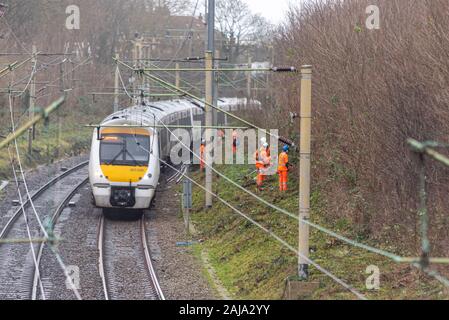 Lavoratori RailScape tagliare vegetazione vicino alla pista del C2C ferrovia in Southend on Sea, Essex, Regno Unito. Modo permanente per equipaggio con il treno che passa Foto Stock