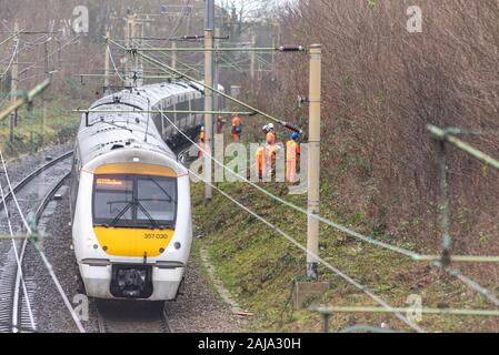 Lavoratori RailScape tagliare vegetazione vicino alla pista del C2C ferrovia in Southend on Sea, Essex, Regno Unito. Modo permanente per equipaggio con il treno che passa Foto Stock