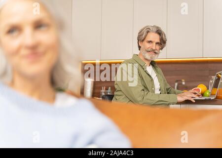 Freelance maschile seduto al tavolo da cucina Foto Stock