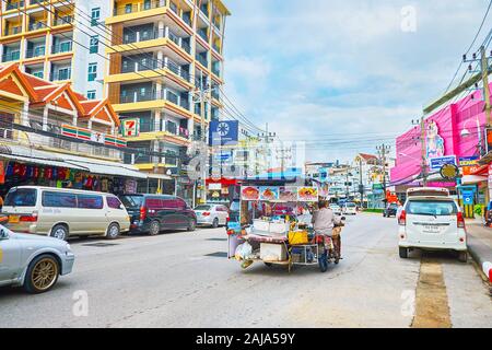 PATONG, Tailandia - 30 Aprile 2019: il traffico nella strada trafficata con una vista sul moderno alloggiamento, le bancarelle del mercato e l'equitazione street food cart, ttached al Foto Stock