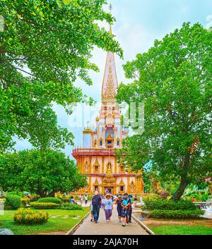 CHALONG, Tailandia - 30 Aprile 2019: il vicolo stretto nel giardino ombreggiato di Wat Chalong con vista sul meraviglioso edificio del Chedi, il 30 aprile in Foto Stock