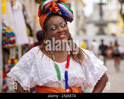 Felice donna brasiliana della discesa africana vestite nei tradizionali costumi Baiana nel centro storico di Salvador de Bahia, in Brasile. Foto Stock