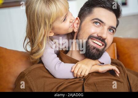 Carina bambina sussurrando qualcosa per padre orecchio Foto Stock