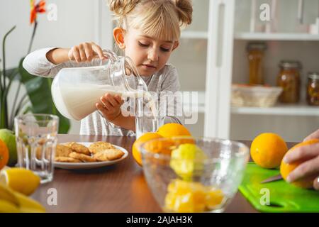 Carina bambina che versa il latte in vetro Foto Stock