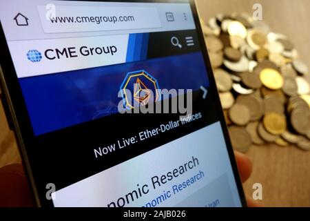 Gruppo CME sito web visualizzato sullo smartphone e la pila di monete Foto Stock