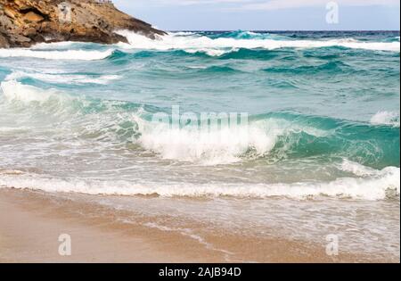 Costa sabbiosa con rocce e onde Foto Stock