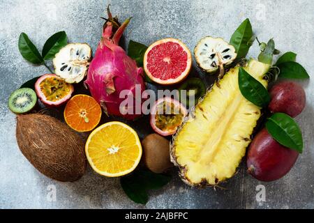 Asia esotica frutta sfondo. Un assortimento di ripe juicy estate tropicale frutta di stagione su una pietra grigia sullo sfondo. Foto Stock
