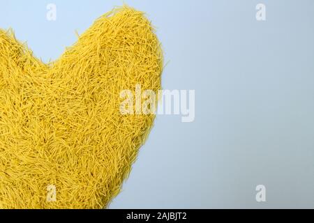 Giallo a forma di cuore la pasta italiana i vermicelli, sfondo romantico per il design e il giorno di San Valentino saluti con copia spazio per il testo Foto Stock