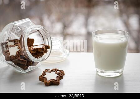 Una gustosa prima colazione o uno spuntino. Un bicchiere di fresco latte organico con biscotti in una forma a stella in inverno la visualizzazione della finestra. Spazio di copia Foto Stock