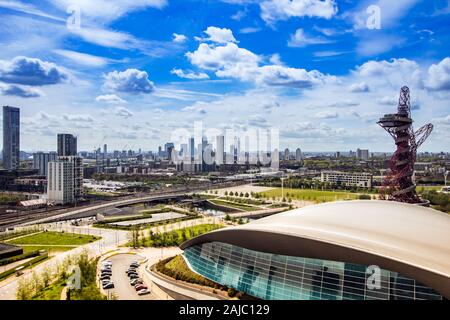 Stratford, Londra, Regno Unito il 3 maggio 2018 Il London Aquatics Centre in primo piano e da Canary Wharf Centro finanziario all'orizzonte. Foto Stock