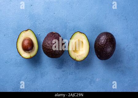 Mezza e intera avocado su sfondo blu Foto Stock