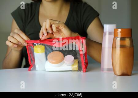 Donna preparare kit da viaggio per il trasporto di prodotti cosmetici su aereo Foto Stock