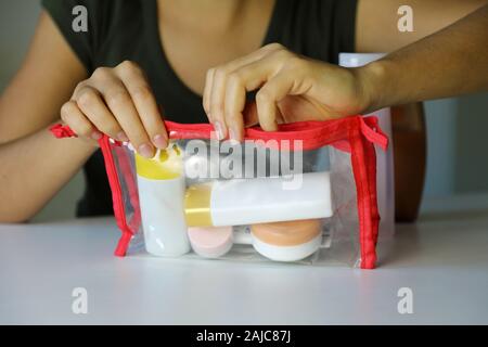 Donna di chiusura sacchetto trasparente con kit da viaggio per il trasporto di prodotti cosmetici su aereo Foto Stock