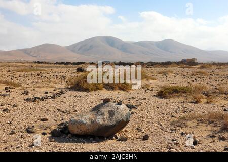 Regione arida arrotondati con le montagne sullo sfondo vista panoramica su isola di Fuerteventura Foto Stock