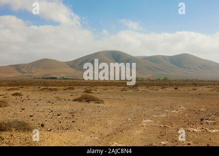 Regione arida terra secca con spigoli montagne sullo sfondo vista panoramica su isola di Fuerteventura Foto Stock