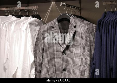 Uomo abiti casual in negozio alla moda di giacche, camicie, cardigan su appendiabiti Foto Stock