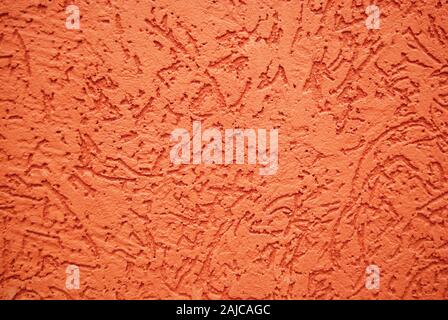 Reddish orange textured background of painted stone wall Foto Stock