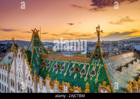 Budapest, Ungheria - vista aerea del tetto colorato della tesoreria di Stato edificio con il Castello di Buda Royal Palace e Golden sunset in background. Tetto Foto Stock