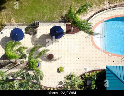 I forti venti soffiano palme come si vede in overhead shot con piscina. Foto Stock