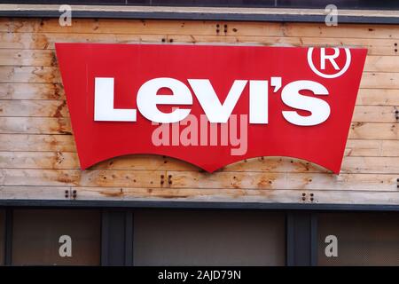 Il logo rosso della Levi's set contro il rivestimento di pannelli di legno presso il proprio negozio in Herald Square a Manhattan, New York, NY. Foto Stock