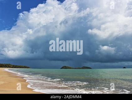 Grandi nuvole e un acquazzone indugiare oltre il doppio di Isola del nord, aspetto di Palm Cove da Clifton Beach in Cairns Queensland Australia Foto Stock