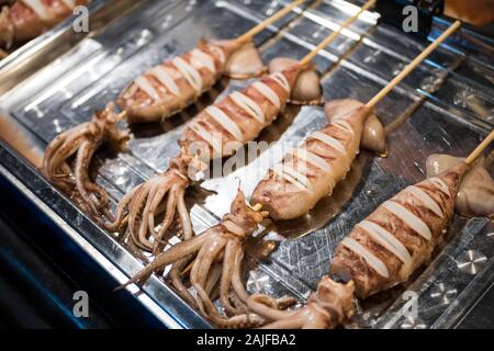 Calamari alla griglia di vendita al cibo in stallo il mercato notturno di Bangkok, Tailandia. Foto Stock