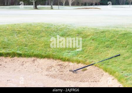 Il rastrello nel bunker di sabbia a golf links corso verde per i golfisti Foto Stock