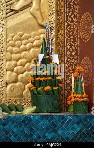 Phakhuan, tempio sacrifici fatti dei rotoli di foglie di banano e calendula fiori, Tripitaka biblioteca, tempio Wat Xieng Thong, Luang Prabang, Laos Foto Stock