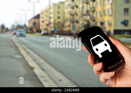 Mano che tiene uno smartphone con una icona di auto, il concetto di car sharing, app per taxi o Uber, auto app Foto Stock