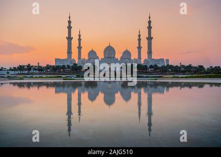 Abu Dhabi, Emirati Arabi Uniti, Emirati Arabi Uniti - Abu Dhabi Moschea Sheikh Zayed (noto anche come grande Moschea) al crepuscolo e la riflessione in acqua, al tramonto Foto Stock