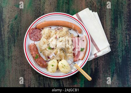 Choucroute garnie, una tipica piastra alsaziano, con salsicce, pancetta, i crauti e patate su sfondo di legno Foto Stock