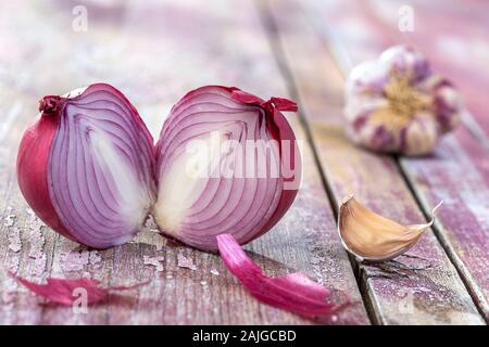 Bello fresco tagliato le cipolle rosse e aglio rosa. gruppo di oggetti o di cottura Ingredienti, isolato su sfondo rosa. Foto Stock