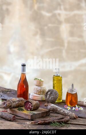 Diverse varietà di Corsica tradizionale di salumi con un ramo di olivo e olive nere su sfondo di legno. Foto Stock