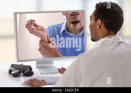 Medico con uno stetoscopio sul computer allo schermo del laptop. la telemedicina o la telesanità concetto, dolore al polso Foto Stock