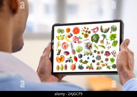 Mangiare sano concetto su un tablet.giovane azienda digitale compressa con cibo sano Foto Stock