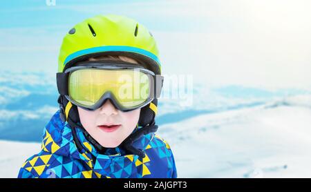 Ragazzo ritratto di moda con moderne attrezzature da sci su ski resort. Cime innevate sullo sfondo. Copia spazio accanto Foto Stock