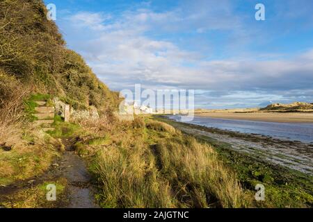 Guardando verso l'interno lungo l'isola di Anglesey sentiero costiero accanto Afon Ffraw river a bassa marea in inverno. Aberffraw, Anglesey, Galles del Nord, Regno Unito, Gran Bretagna, e Foto Stock
