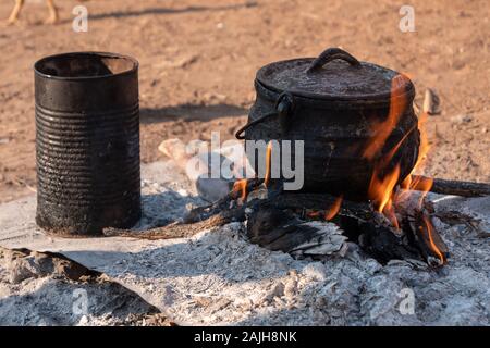 Vecchio, poco paiolo di rame e stagno su Campfire - nativo di base di tutti gli utensili da cucina di tribù Himba, Namibia, Africa Foto Stock