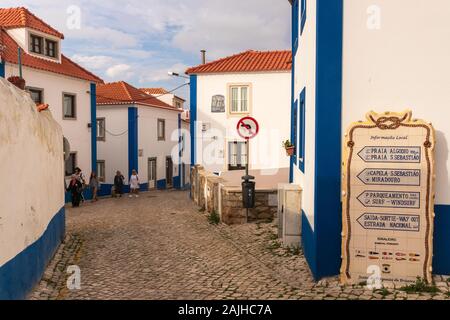 Una delle pittoresche strade di Ericeira, 45 minuti da Lisbona, con le tradizionali case bianche con strisce blu Foto Stock