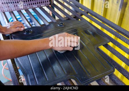 Pulire la moquette nera della vettura con una soluzione detergente usando una spazzola di lavaggio. Foto Stock