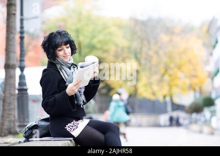 giovane donna che legge in un libro fuori Foto Stock