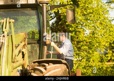 Donna contadina che sale su un trattore Foto Stock