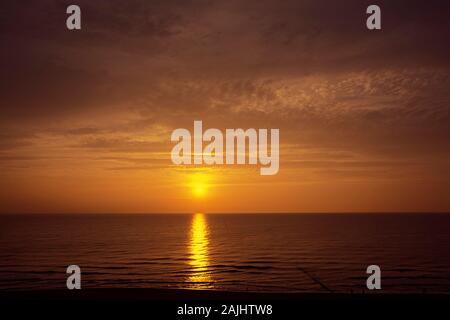 Untergehende Sonne zwischen Meer und Wolken am Strand bei Wenningstedt auf Sylt Foto Stock