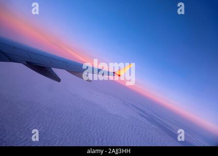 Tramonto su Sky e ala del piano, vista dalla finestra del velivolo, come sfondo Foto Stock