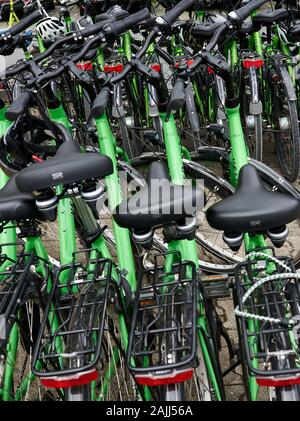 Primo piano di una massa di biciclette impilate l'una contro l'altra pronte per un noleggio ecologico nel centro di Berlino, in Germania. Foto Stock