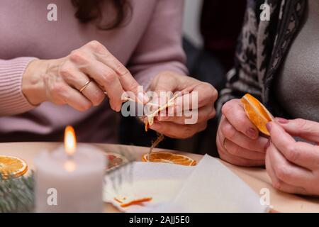 Le donne la mano facendo decorazioni da essiccato arance, stelle dal mandarino e cannella. Girls party o riunione. Foto Stock