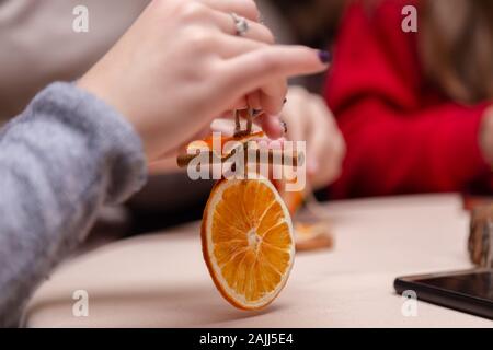 Le donne la mano facendo decorazioni da essiccato arance, stelle dal mandarino e cannella. Girls party o riunione. Foto Stock